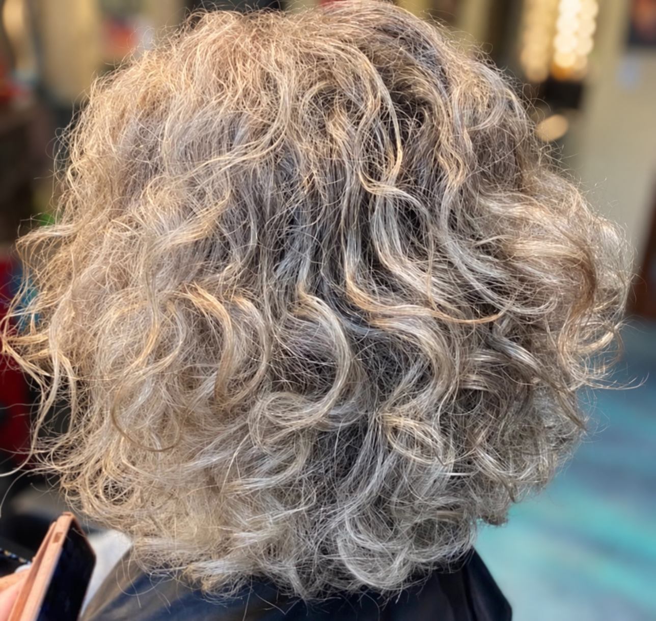 Short silver-gray hair with loose curls and natural texture, styled by Kellie